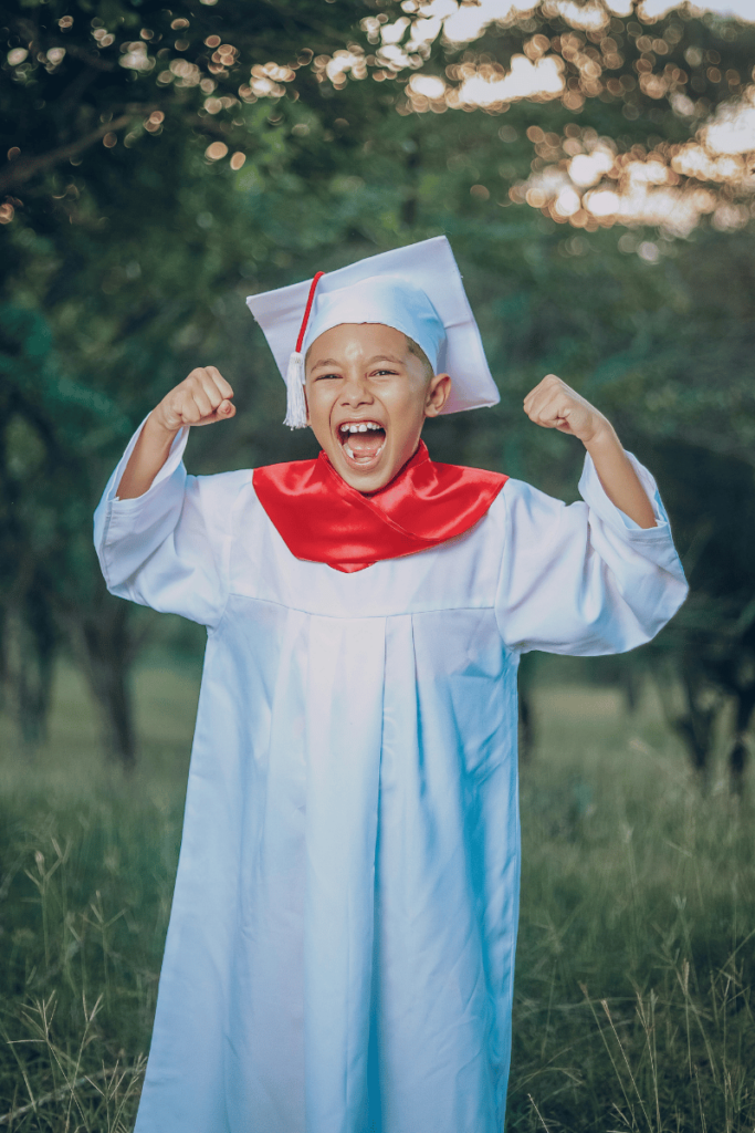 529 Plans: An enthusiastic child poses in graduate cap and gown.